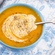 carrot soup in a blue bowl on a wooden table